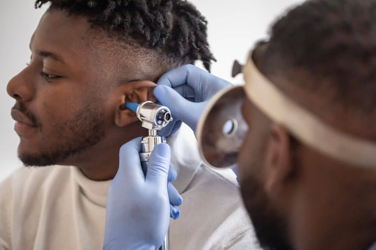 Man having his ear inspected for a perforation by his doctor