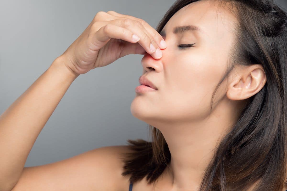 Woman holding the bridge of her nose due to pain caused by sinusitis