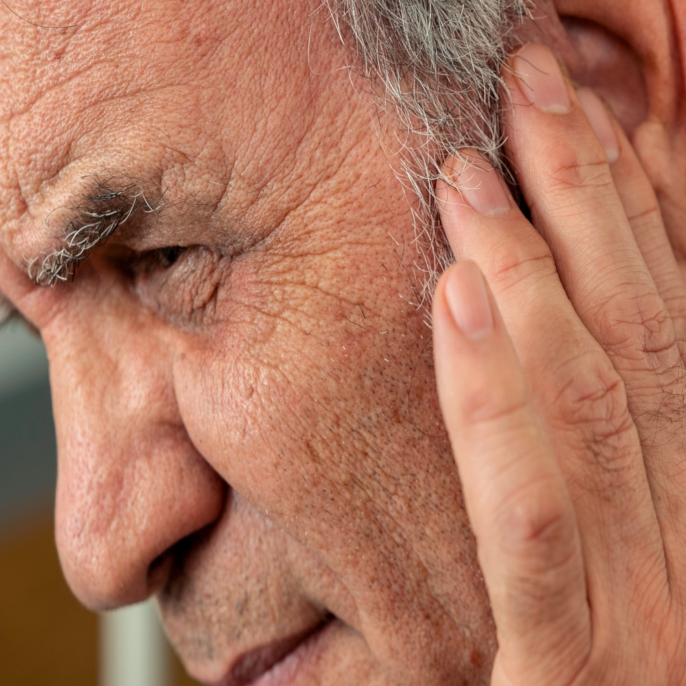 a man puts his hand to his ear in discomfort