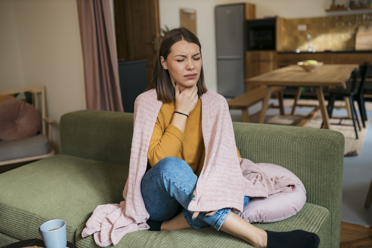 Woman with postnasal drip holding her throat.