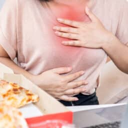 Woman with heartburn holding her chest.