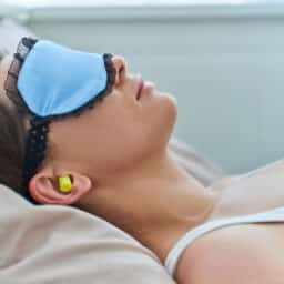 Woman wearing earplugs and eye mask for better sleeping