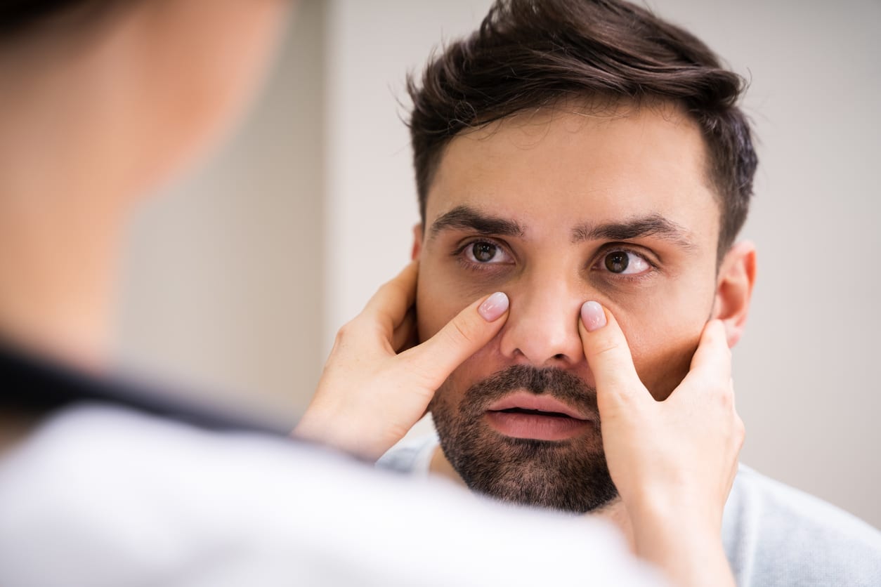 Doctor examines man's sinus pressure
