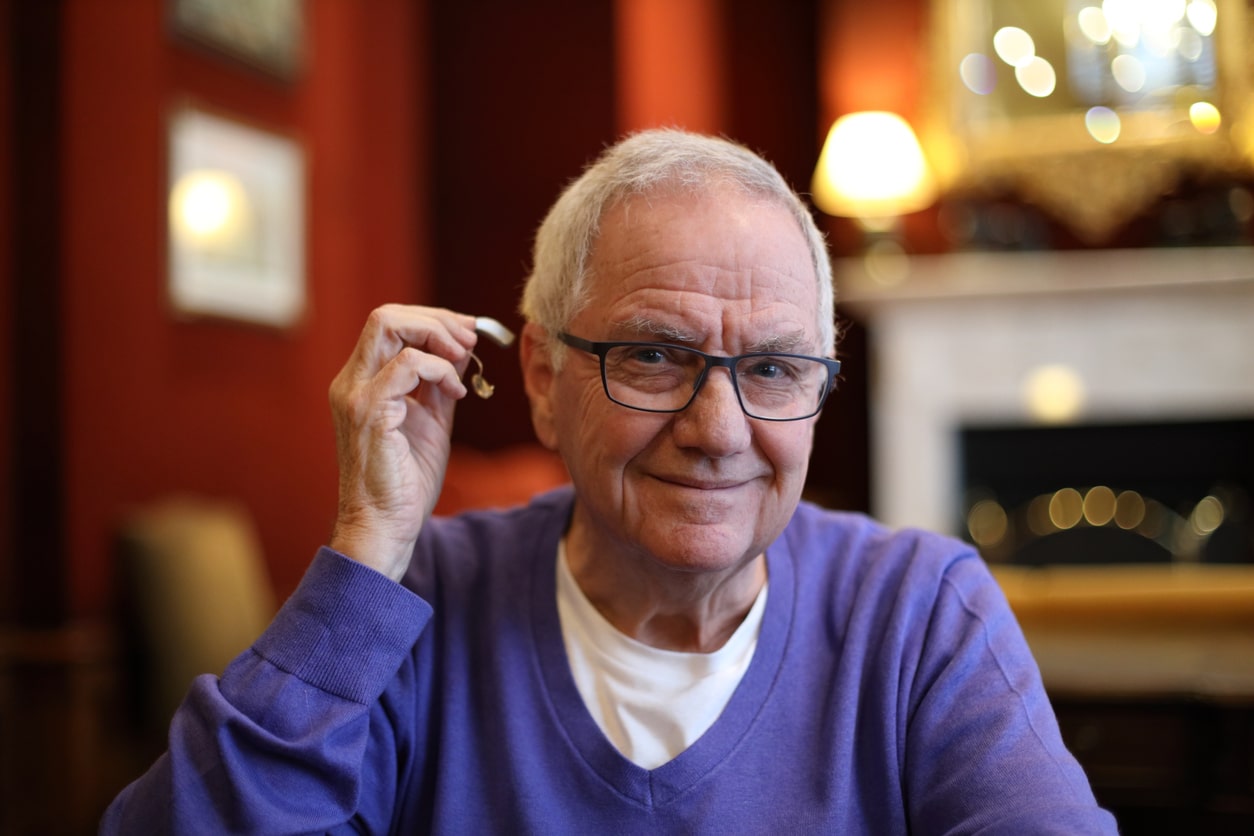 Man shows off his hearing aid in a lovely living room before Thanksgiving dinner.