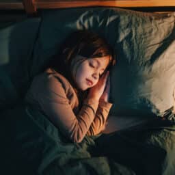 Young girl sleeping peacefully on her side in a big cozy bed.
