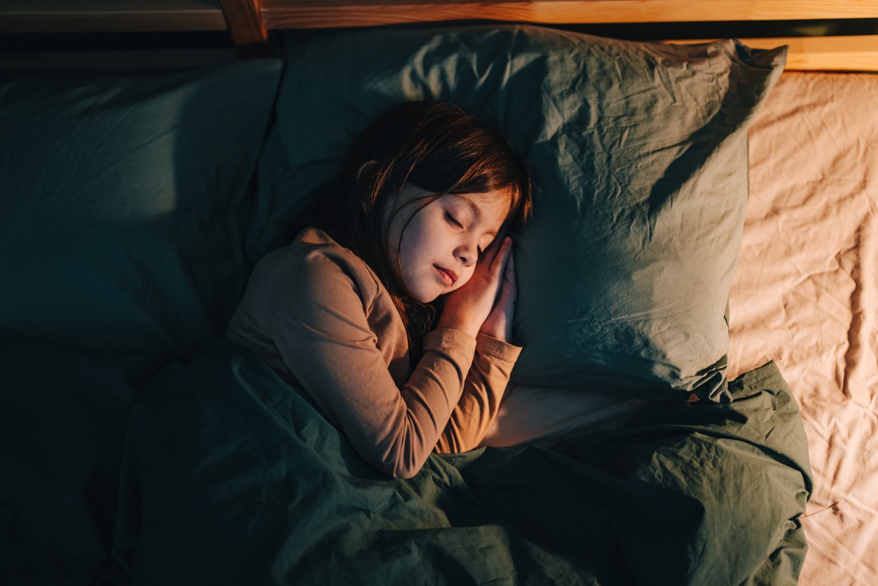 Young girl sleeping peacefully on her side in a big cozy bed.