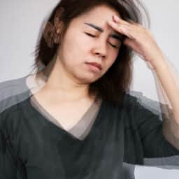 Person experiencing dizziness holds their head and looks uncomfortable.
