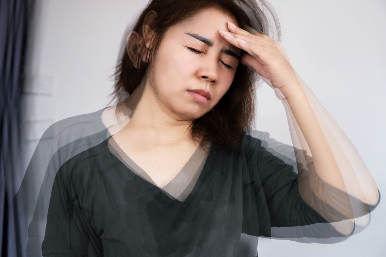 Person experiencing dizziness holds their head and looks uncomfortable.